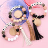 A set of leopard print silicone bead keychains in pink, black, and white are arranged on a pink background.
