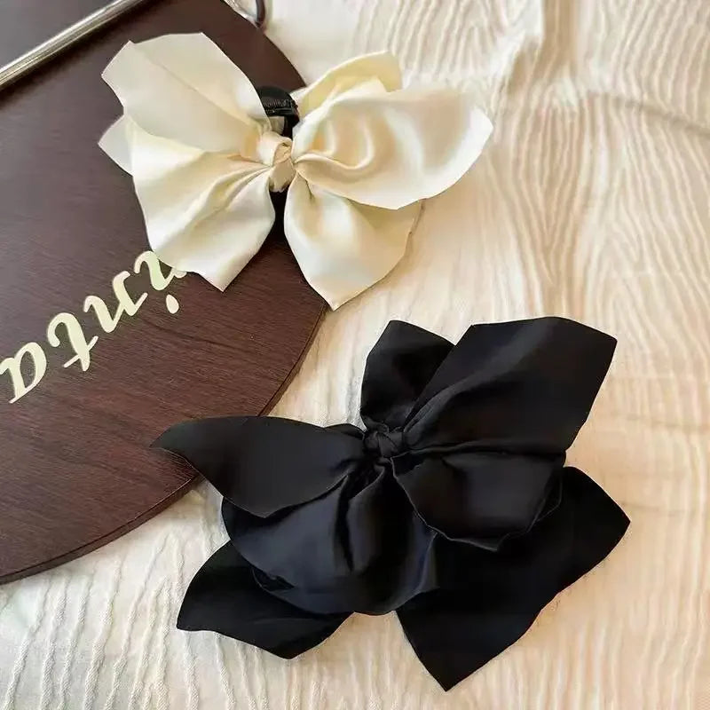 Un lazo negro y una cinta crema se exhiben sobre una superficie de madera oscura.
