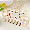 A set of five gold-toned bracelets featuring various enamel colors including red, black, green, and pink blossoms.