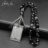 A black beaded necklace with a stainless steel Quran Arabic car pendant on a dark background.