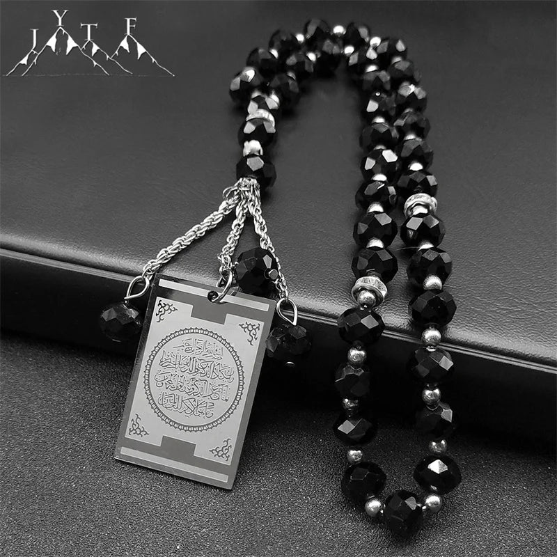 A black beaded necklace with a stainless steel Quran Arabic car pendant on a dark background.