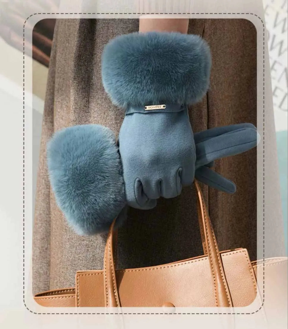 A close-up of a pair of plush, fuzzy blue wrist gloves being held against a brown garment.