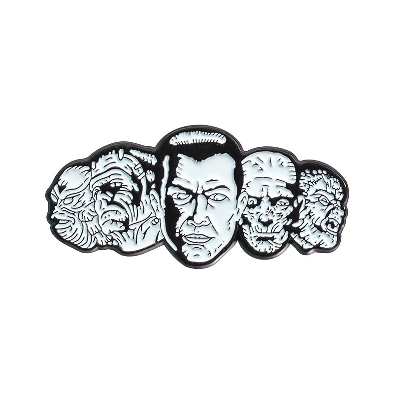 Eine Sammlung von schwarz-weißen Emaille-Pins mit monströsen oder horror-inspirierten Gesichtern.