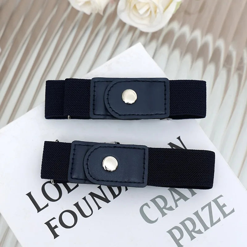 A black buckle-free elastic casual belt is displayed on a white surface with floral accents.