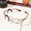 A close-up of a rose gold fashion acetate toothed headband resting on a white surface.
