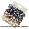 A set of five satin hair scrunchies in various shades of gray, pink, and white displayed on a cardboard backing.