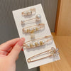 Gold-toned pearl brooch pins displayed on a white card against a blurred background.