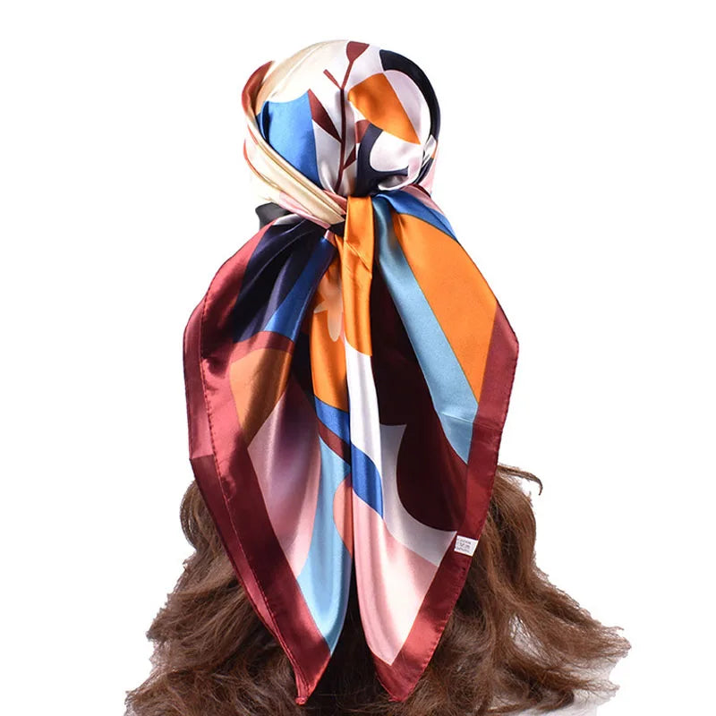 Luxuriöser Seidenschal in Orange, Blau und Braun um das Haar einer Frau gebunden.
