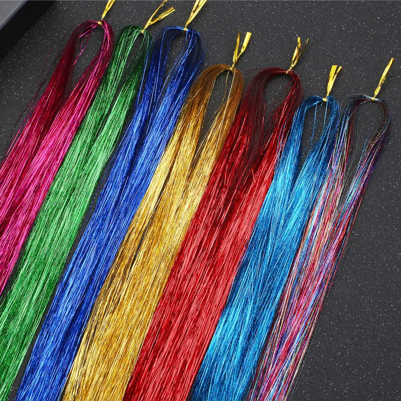 A collection of twelve strands of synthetic hair tinsel in various colors including pink, green, blue, gold, and red.