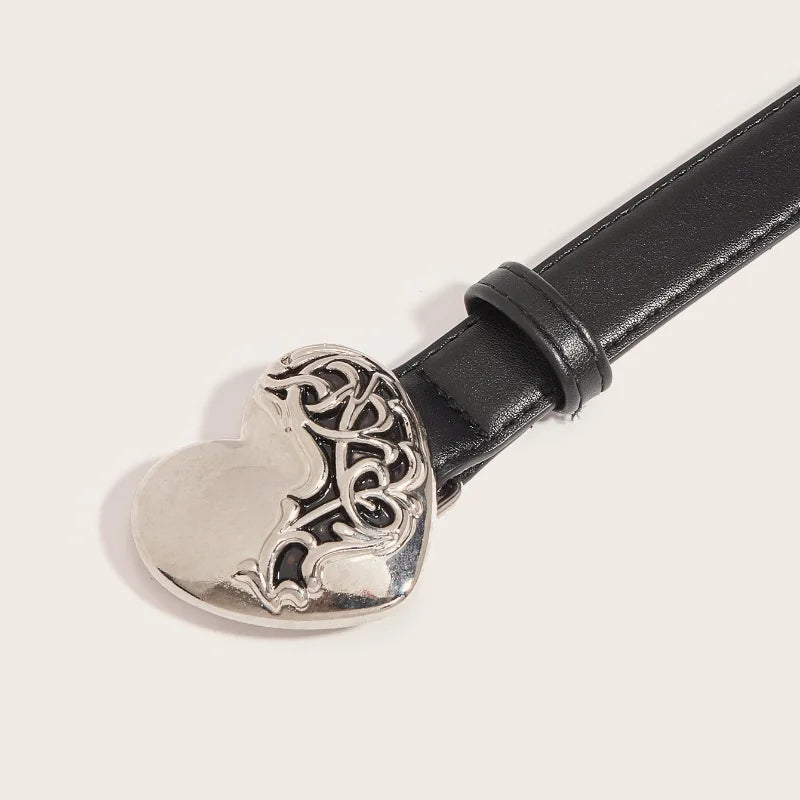 Cinturón de cierre de corazón de metal vintage con diseño ornamentado, sujeto a una correa de cuero negro.