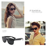 A woman models black polarized sunglasses and a yellow shirt outdoors.
