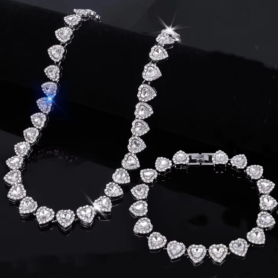 A set of sparkling heart rhinestone necklaces and bracelets displayed on a black surface.