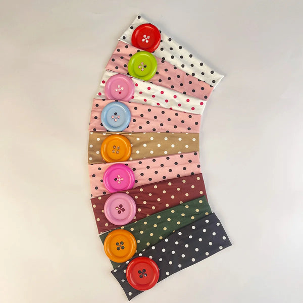 A display of vintage polka dot button headbands in various shades of pink, green, and brown arranged in a fan shape.
