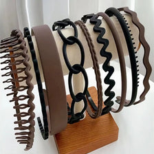 A display of various brown and black hair accessories headbands arranged on a wooden stand.