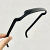 A black sleek hair stick is being held by a hand, showing the elegant styling tool.