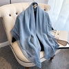 Light blue shawl with bohemian lace trim draped over a cream upholstered chair.