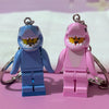 A pair of heart-shaped building block keychains featuring shark figures in blue and pink.