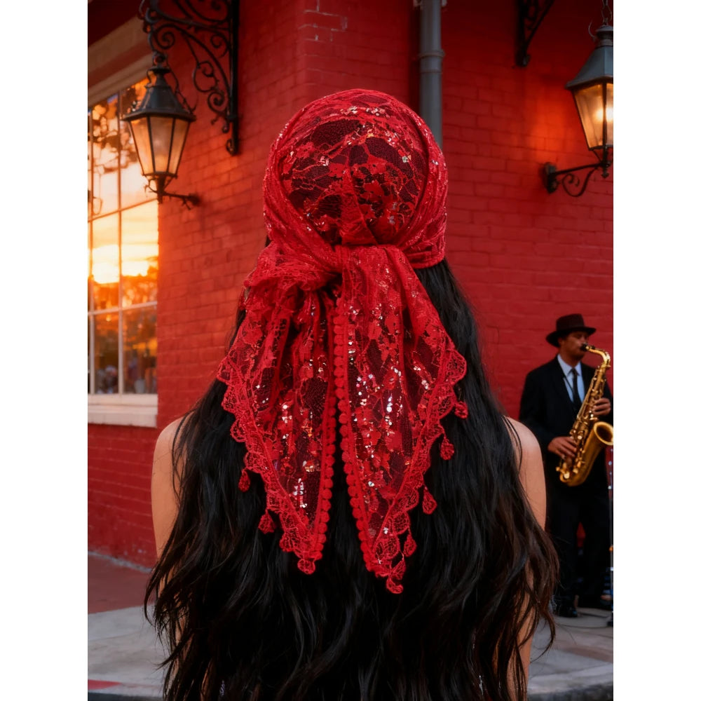 Eine Frau mit langen dunklen Haaren trägt einen leuchtend roten bestickten Seiderschal, gebunden als Turban, vor einer Backst