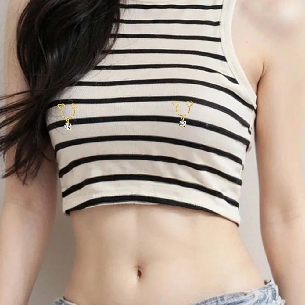 A close-up of a beige striped crop top featuring heart dangle non-piercing nipple rings with cubic zirconia.