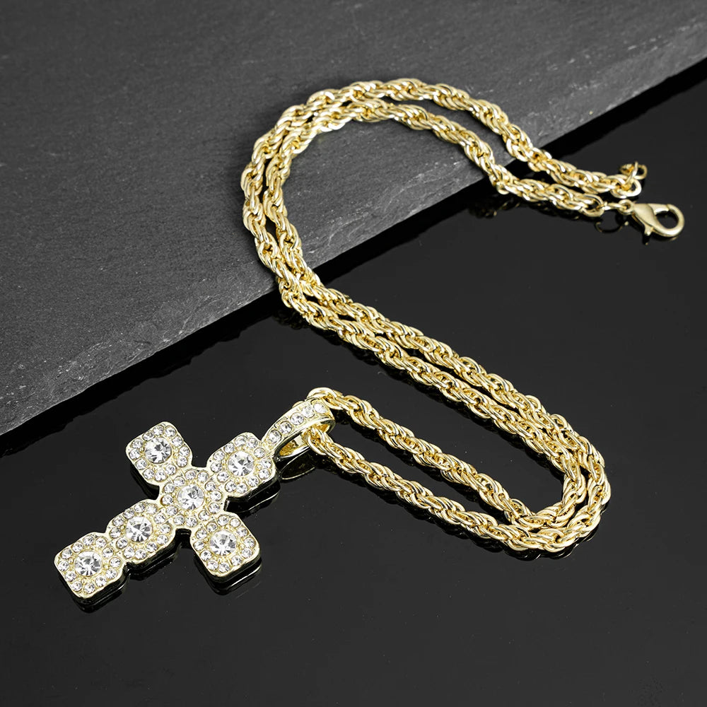 Gold chain necklace with a sparkling rhinestone cross pendant displayed on a black surface.