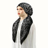 A woman models a black leopard print satin silk hijab headband cap with a white top.