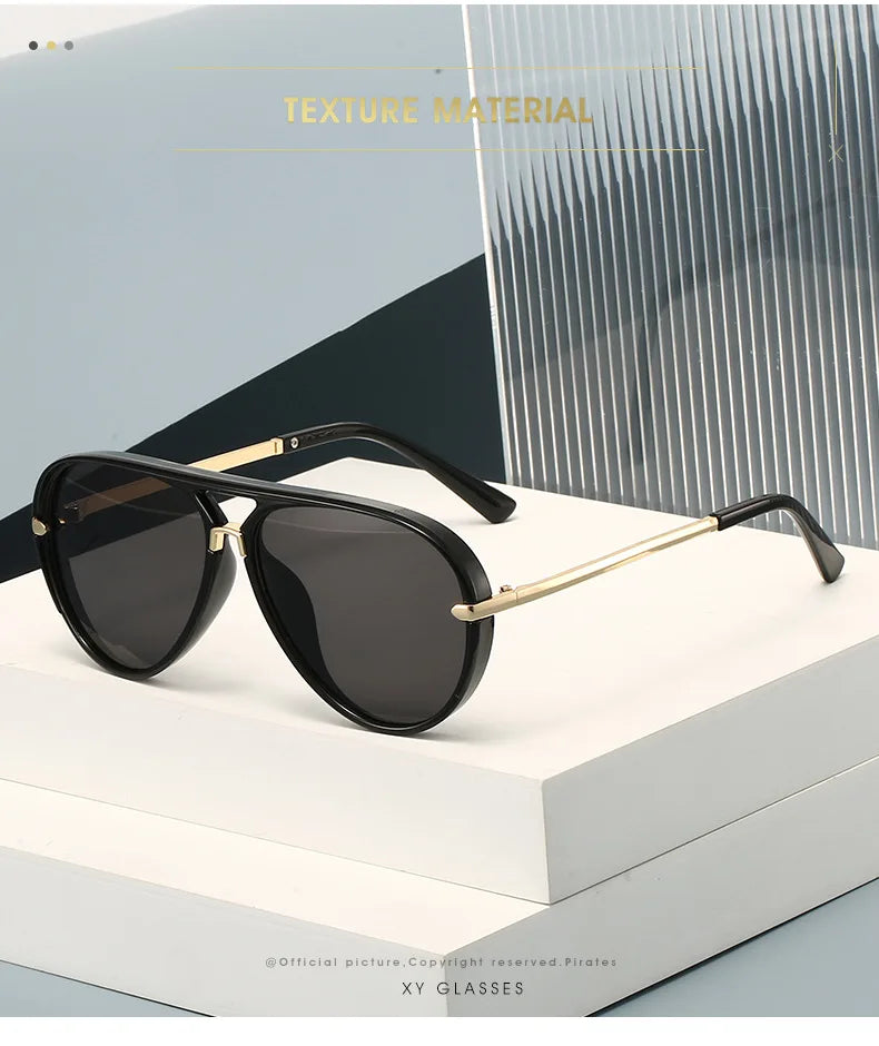 A pair of black aviator-style sunglasses with gold accents resting on a white surface.