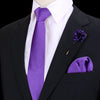 Chaqueta negra, camisa blanca, corbata de seda púrpura y pañuelo de bolsillo de seda púrpura con un broche pequeño.