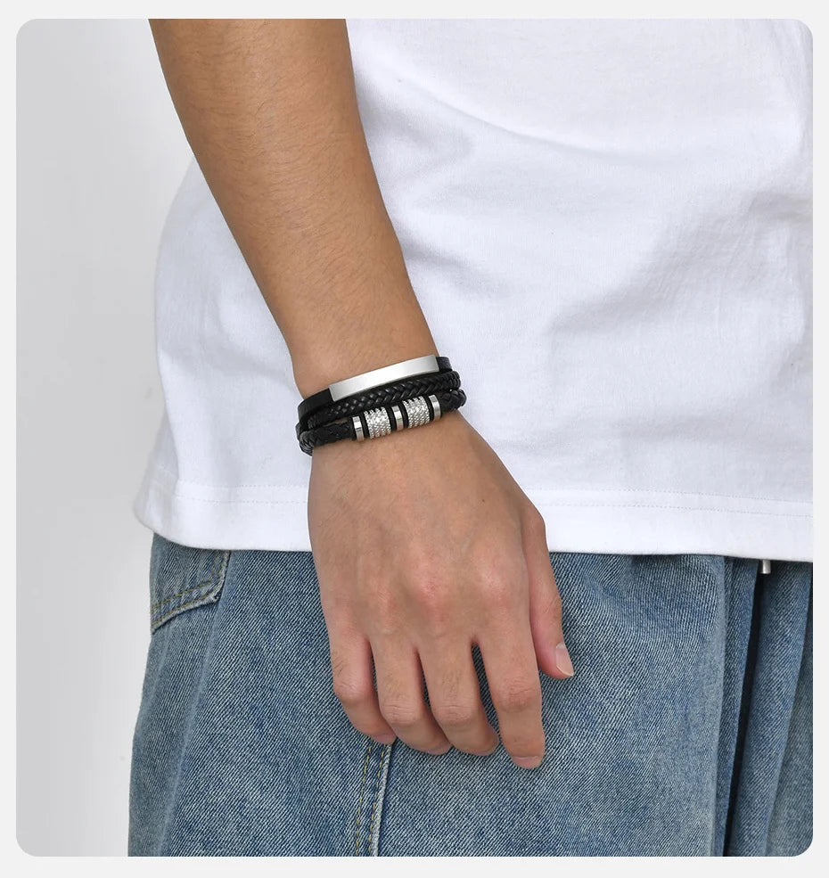 Nahaufnahme eines Mannes Handgelenks mit einem schwarzen geflochtenen Lederarmband an einem weißen T-Shirt.
