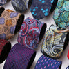 A collection of six patterned men's formal ties and accessories in various floral and geometric designs.