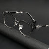 Une paire de lunettes noires avec des détails argentés posée sur une surface sombre.