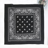 Black fabric with white paisley embroidery featuring a central square design and ornate borders.
