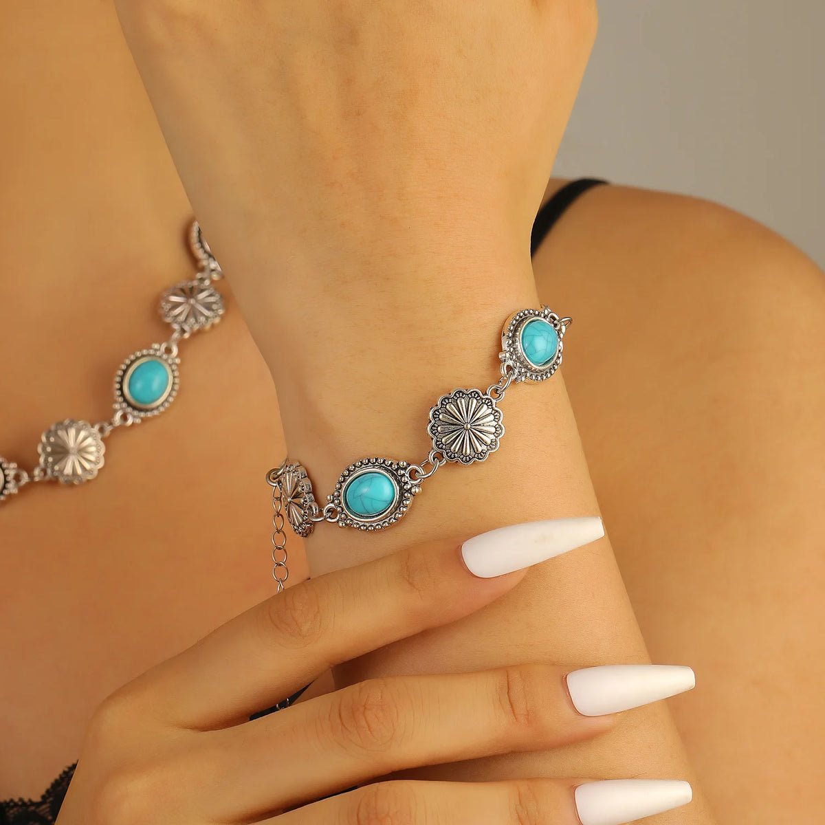 A silver beaded necklace and bracelet set featuring turquoise flower-shaped beads worn on a wrist.