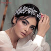 A woman models a silver crystal bridal headband woven into her dark hair, wearing sheer white fabric.
