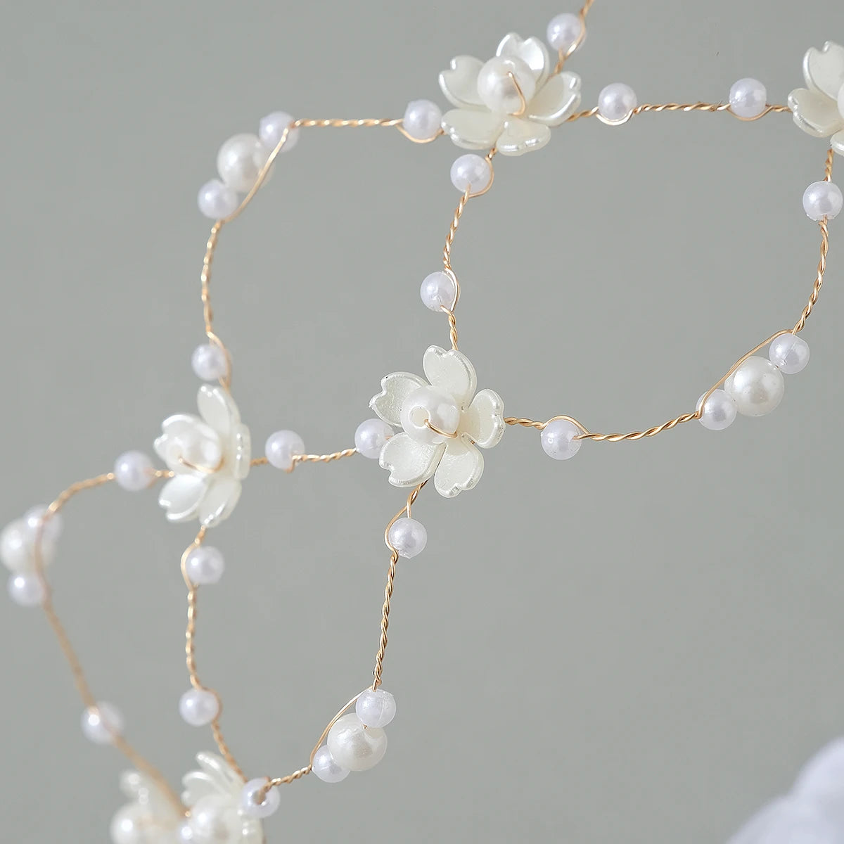 Elegant pearl hair net headband featuring small white flowers and delicate gold wire.