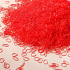 A pile of bright red disposable rubber hair ties for kids scattered on a light surface.