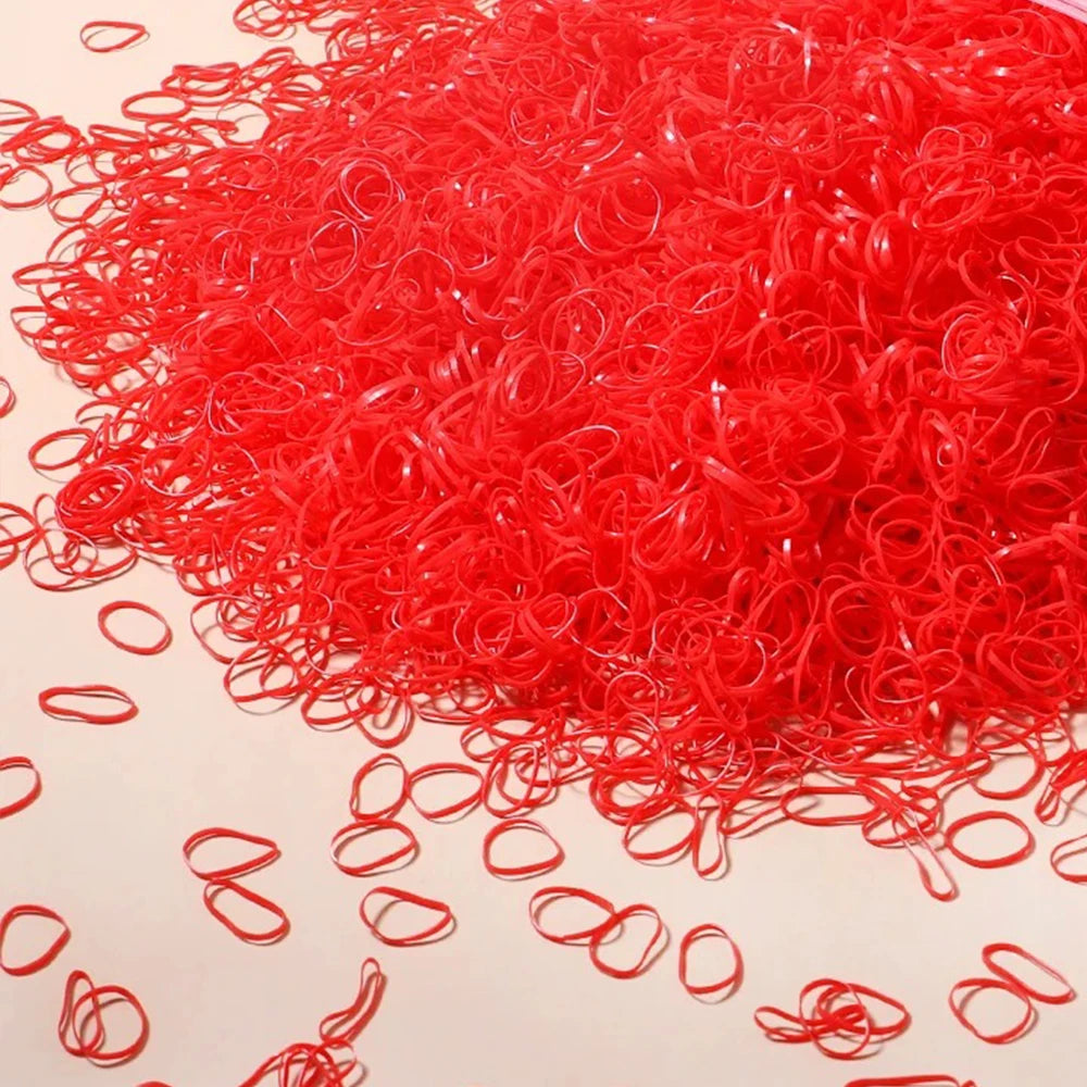 A pile of bright red disposable rubber hair ties for kids scattered on a light surface.