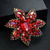 Broche florale en cristal rouge ornée de nombreuses pierres taillées, montée en métal doré.