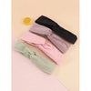 Ein Set von vier weichen Stoff-Haarbändern in Schwarz, Lila, Pink und Mintgrün auf hellem Hintergrund.