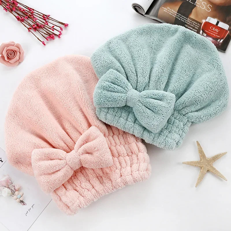A pink and mint green microfiber hair drying towel with a bow is shown on a white background.