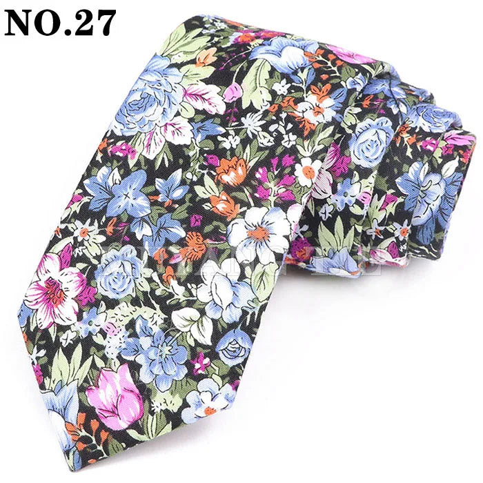 Gros plan d'une cravate en coton à imprimé floral avec des fleurs bleues, roses et vertes sur fond noir.
