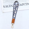 Brauner Leder-Handy-Lanyard mit gemustertem Stoffriemen und Metallclip.