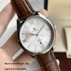 Gros plan d'une montre quartz pour homme avec boîtier argenté et bracelet en cuir marron tenue par une main.
