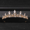 Gold-toned Baroque crystal rhinestone bridal tiara headpiece displayed on a dark surface.