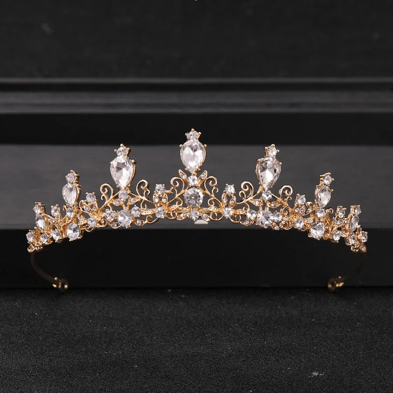 Gold-toned Baroque crystal rhinestone bridal tiara headpiece displayed on a dark surface.