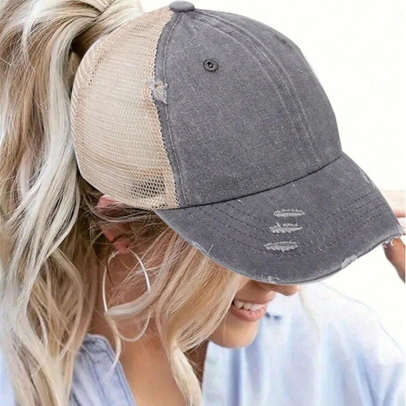 A woman is wearing a vintage mesh baseball cap with a grey front and a beige mesh panel.