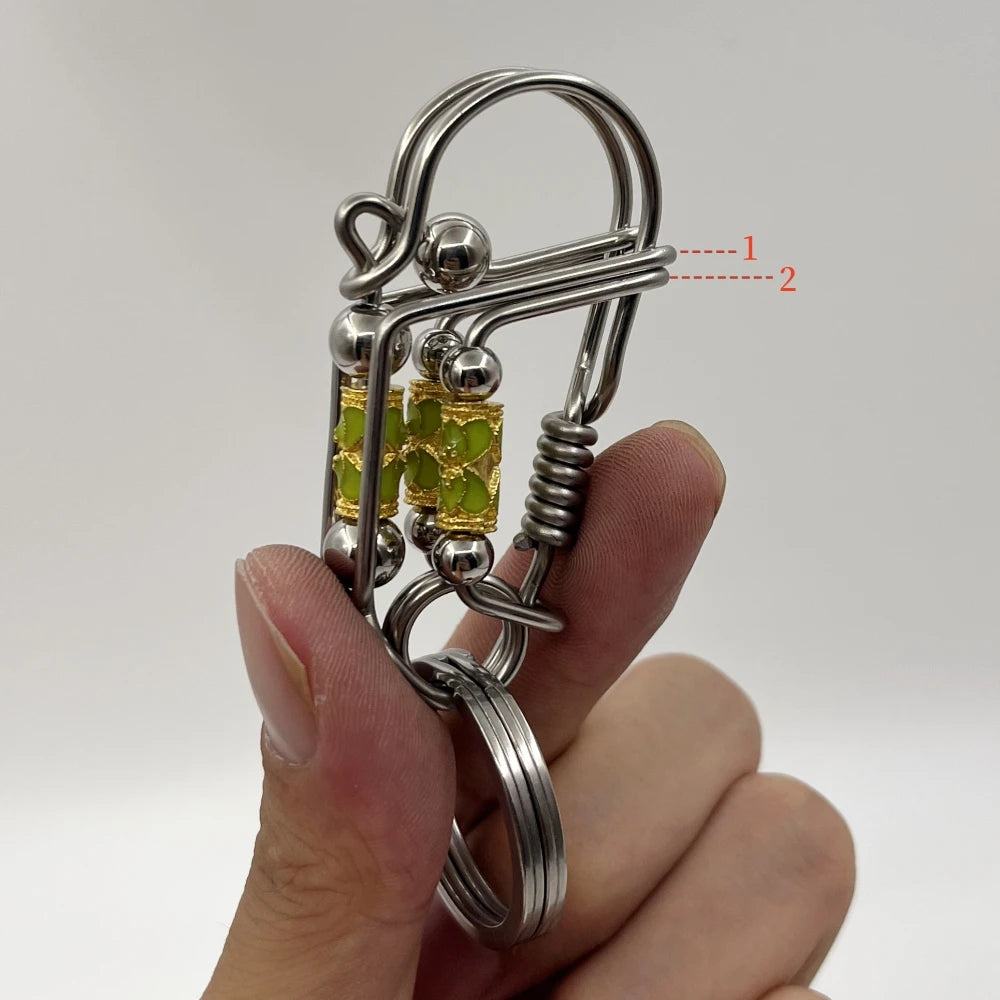 Un porte-clés mécanique en acier inoxydable avec un charm de couleur or est tenu dans la main d'une personne.