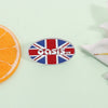 Broche émail avec le drapeau du Royaume-Uni et le mot Oasis en blanc sur fond argenté.