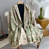 A light green and beige plaid cashmere scarf draped over a white chair.