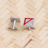 Pince-cuffs carrés argentés avec un motif rayé rouge et blanc posés sur un dessous en bambou clair.