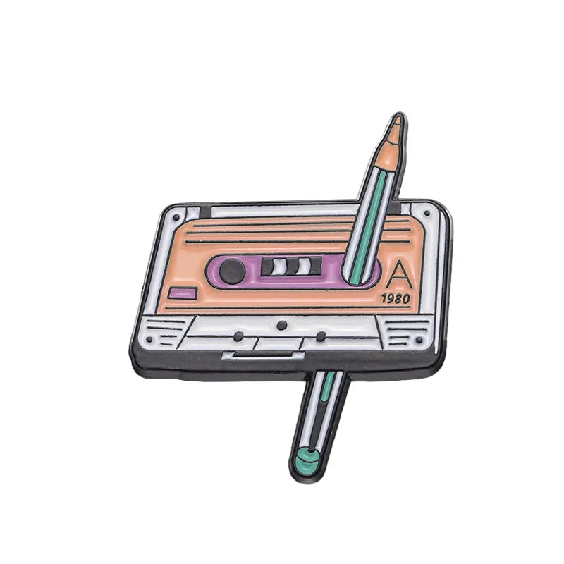 A retro fine line cassette enamel pin brooch featuring a cassette tape and a pencil.